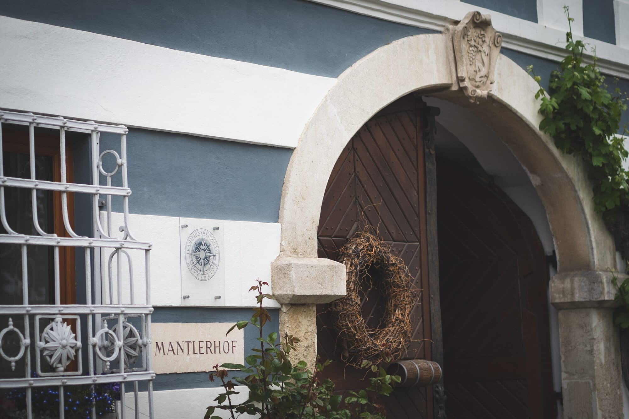 Entrance of Mantlerhof with the MANTLERHOF sign and roses